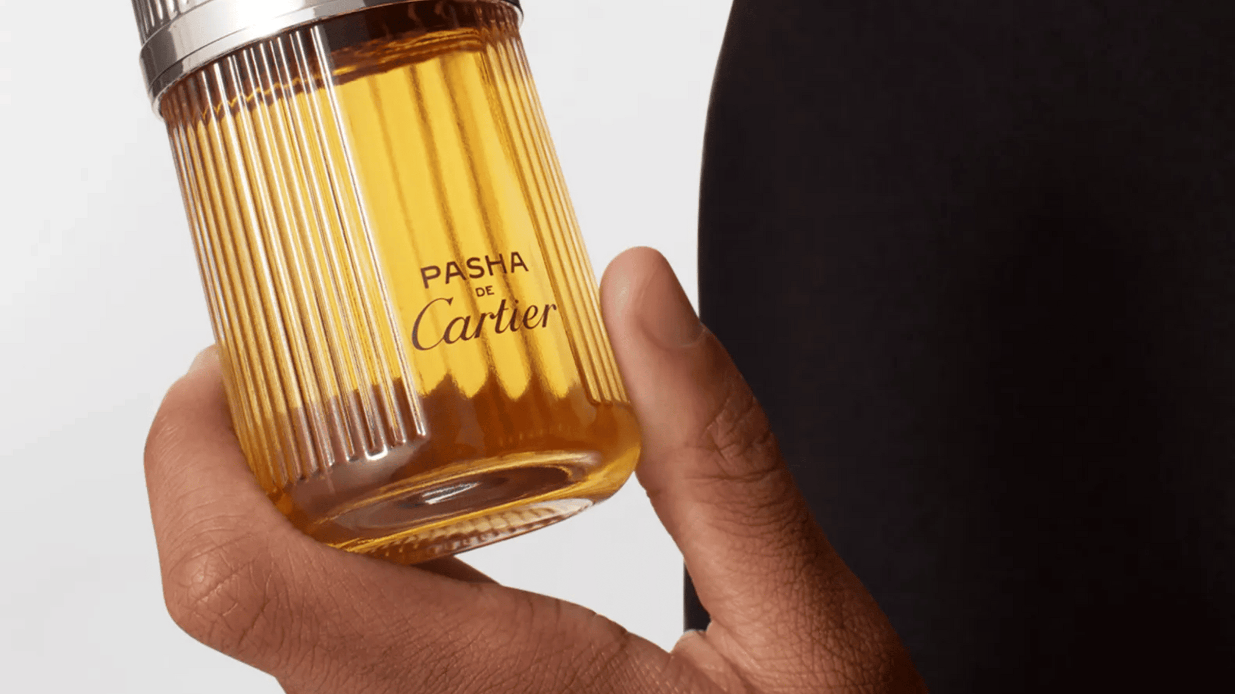 En hand som håller i en Cartier parfym
