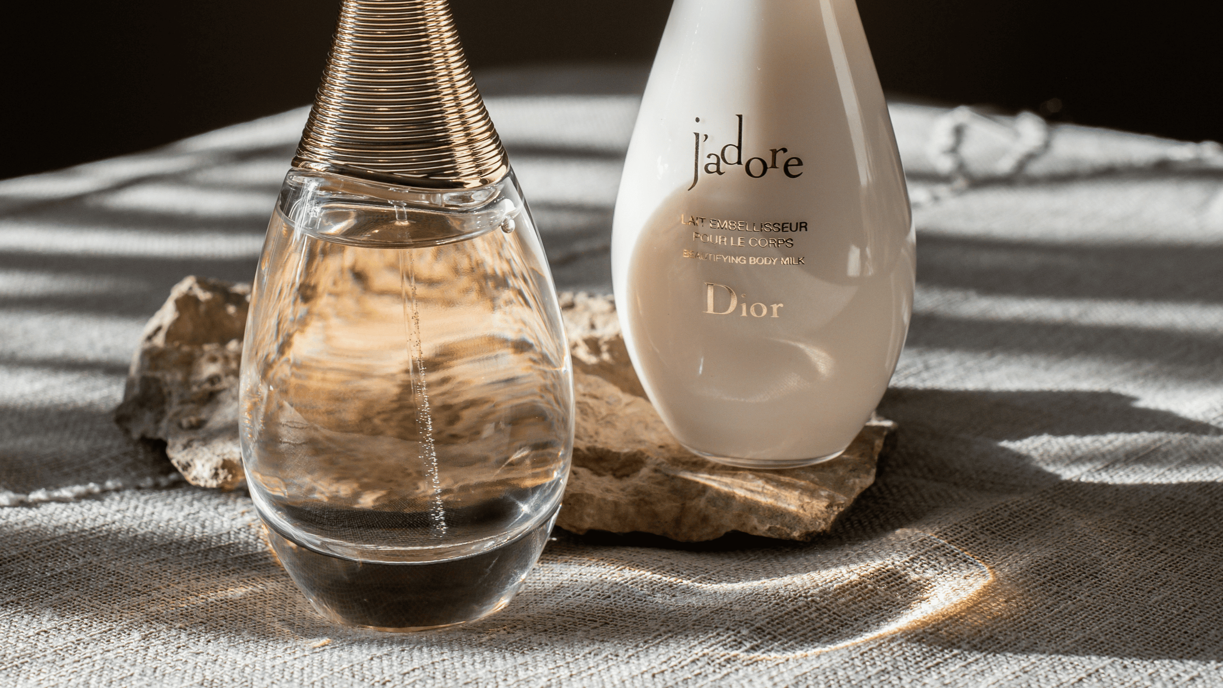Bild på parfymen Jadore från Dior, som står på en sten i solen.