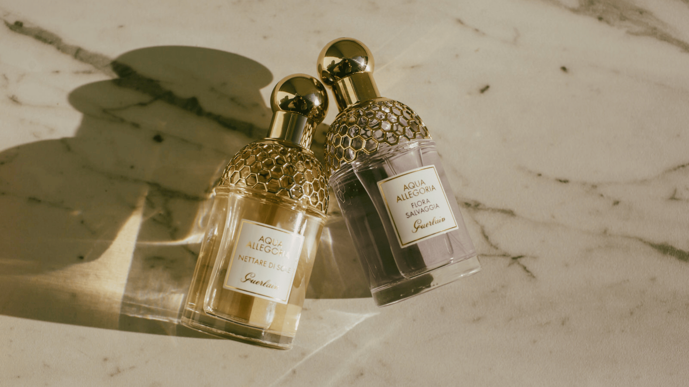 Två parfymer från Guerlain som ligger på ett stenbord.